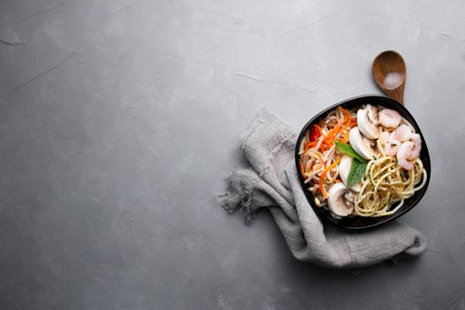 A top view of noodles with vegetables isolated on a white background
