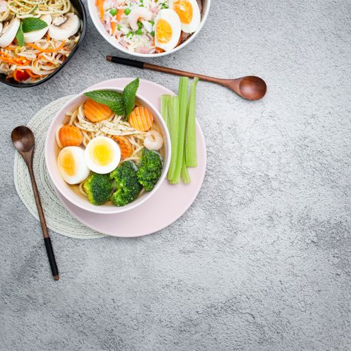 A top view of different dishes with noodles, eggs, and vegetables in bowls