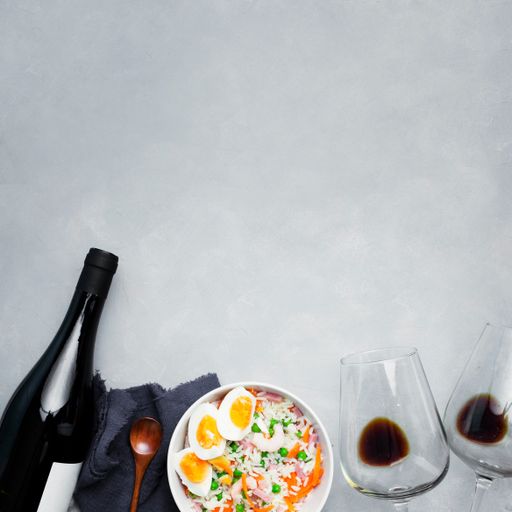 A top view of noodles with vegetables and a bottle of wine