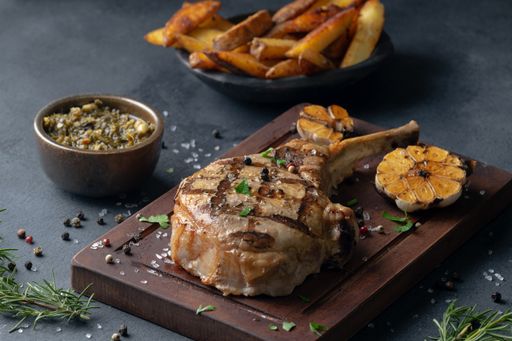A closeup shot of a seasoned stake on a board served with fries