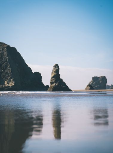 A scenic view of sea stacks and cliffs at Bandon Beach, Oregon under a clear blue sky