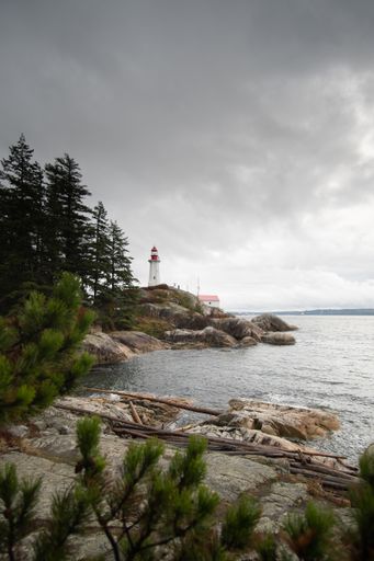 A lighthouse on a rocky coast in West Vancouver during cloudy weather
