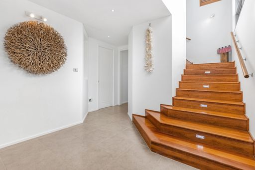 A modern interior hallway with wooden staircase and decorative wall art in a contemporary home.