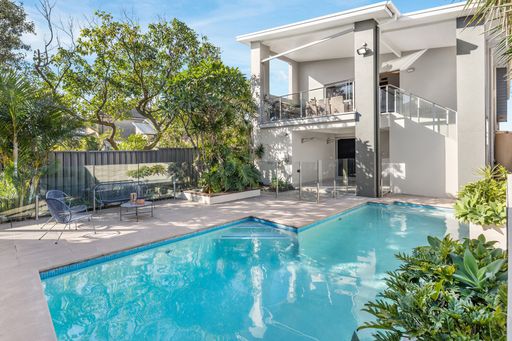 A modern house with a swimming pool and outdoor seating area surrounded by lush greenery.