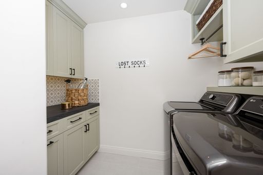 Modern laundry room with washing machines, storage cabinets, and a 'Lost Socks' sign on the wall.