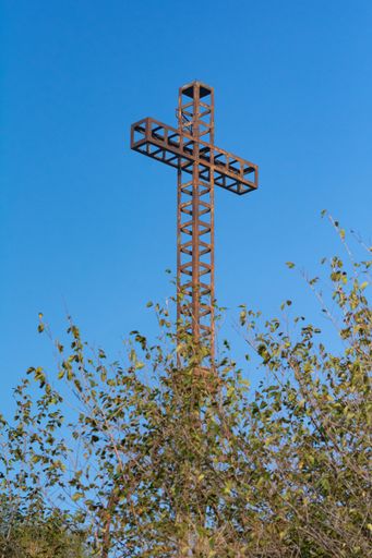 A vertical shot of the old rustic metal cross placed on the mount of San Bartolo in Italy