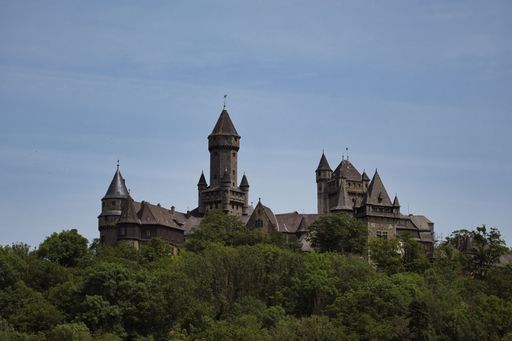 A scenic view of Braunfels Castel in Hesse surrounded by lush greenery under a clear blue sky.