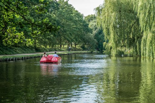 Two people on a pedal boat sailing on a river in the Munke Mose Park, Odense, Denmark
