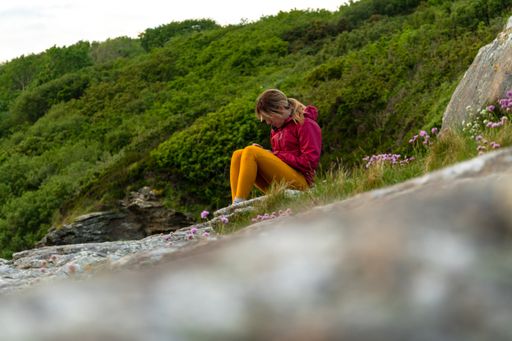 A female using her phone sitting on the beach