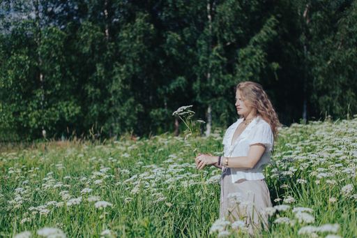 A young woman posing in a field of white wildflowers on a sunny day