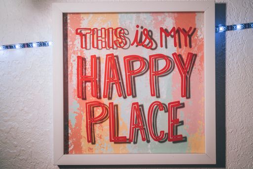 A closeup shot of a framed picture with the text "this is my happy place" on the wall