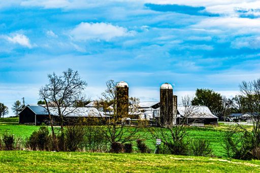 A scenic view of a rural farm with silos and barns under a vibrant blue sky in Pensacola, Florida