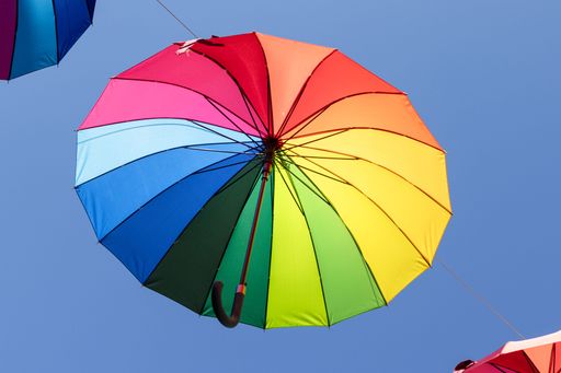 Colorful umbrellas hanging in the air as urban decoration representing LGBTQ pride parade. Low angle shot