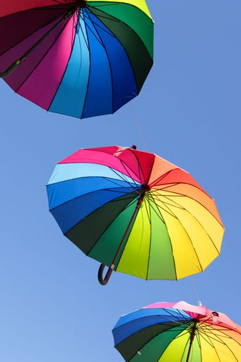 Colorful umbrellas hanging in the air as urban decoration representing LGBTQ pride parade. Low angle shot