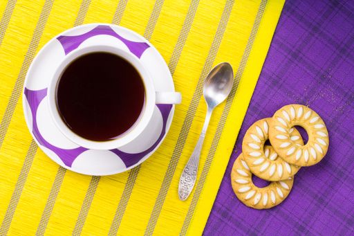 A top view of tea with cookies on yellow and purple background