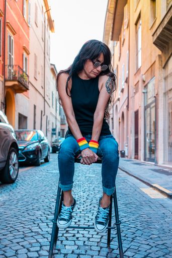 An attractive youthful Hispanic female in sunglasses sitting on a chair in the middle of a street