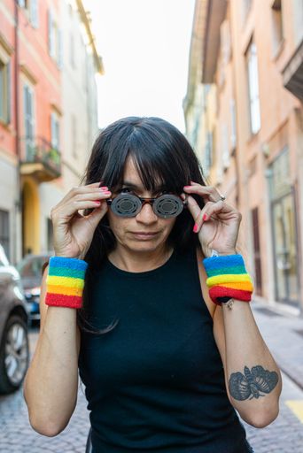 An attractive youthful Hispanic female in sunglasses sitting on a chair in the middle of a street
