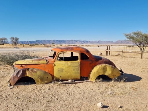 An old broken vintage car thrown in a desert