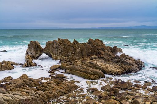 A coastline with waves crashing against the rocks under a cloudy sky at Pacific Grove, California
