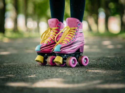 A pair of pink roller skate worn by a female kid on the footpath
