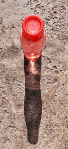 A vertical high angle shot of the shadow of a plastic water bottle stretched on the ground