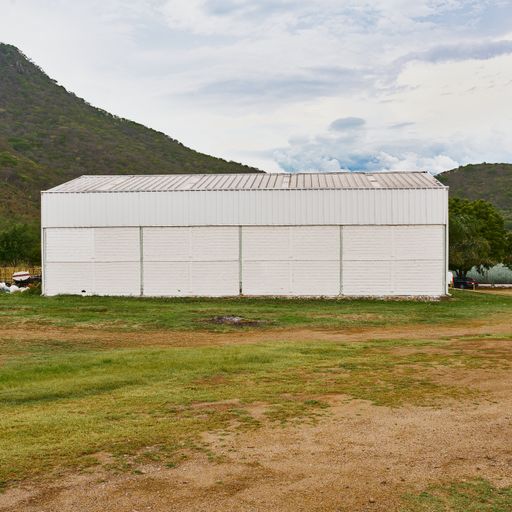 warehouse to store and manufacture products, within a field near a hill with a very beautiful sky