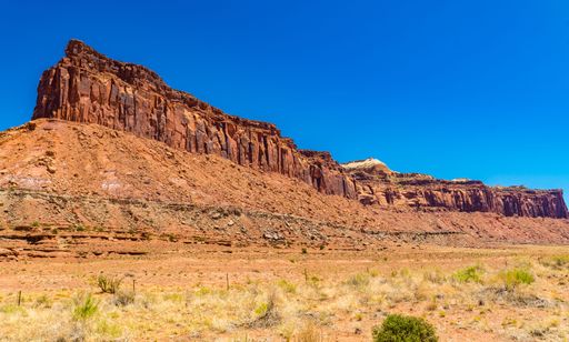 A stunning view of a red rock formation under clear blue sky on a sunny day in Canyonlands National Park, Utah, USA