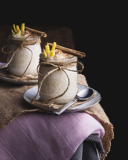 A vertical shot of two classic cups and saucers with Arroz con leche on a dining table