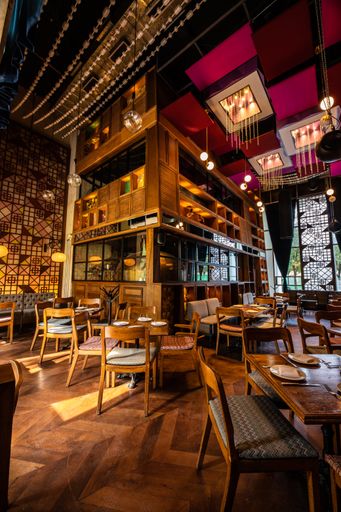 A vertical shot of the interior of a cozy restaurant with wooden flooring and warm orange hanging lights