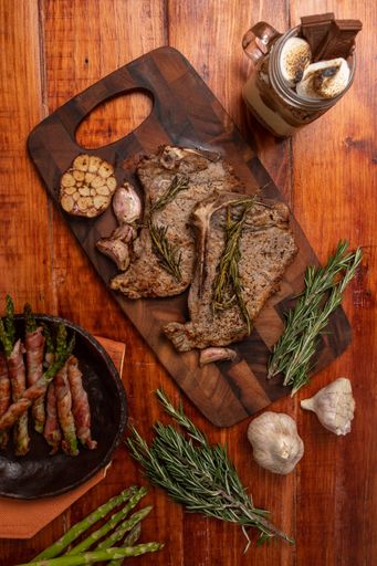 An overhead shot of an appetizing steak and bacon wrapped asparagus on a wooden table