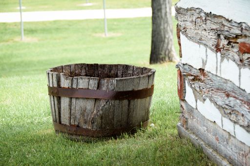 An old wooden barrel next to a rustic building on a grassy lawn in Black Hills National Forest
