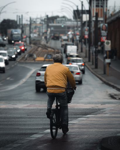 A man in a yellow jacket riding a bicycle in Berlin, Oberbaumbrucke, Germany