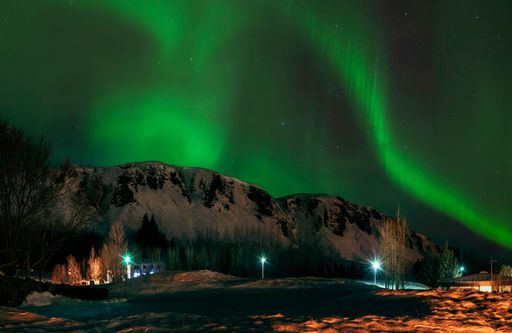 A stunning view of the Northern Lights over a snow-covered mountain landscape at night in Iceland