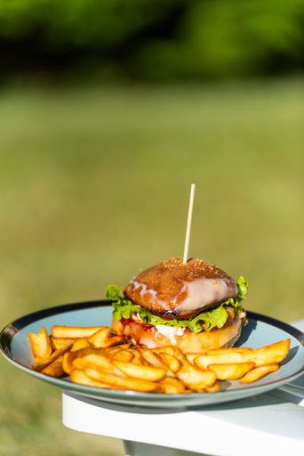 A vertical shot of a hamburger and potato fry on a plate isolated on a plastic lounge chair
