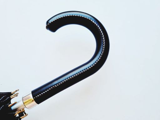 A black leather handle detail of an umbrella isolated on a white background with free space for text