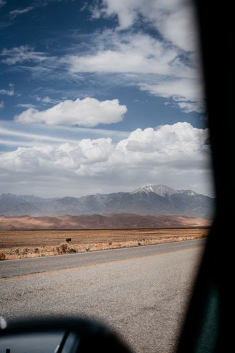 A vertical shot of a road and a beautiful mountain view through a window of a car