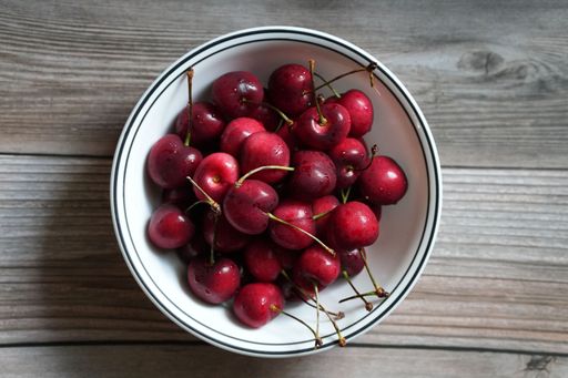 A bowl of fresh red cherries on a wooden table