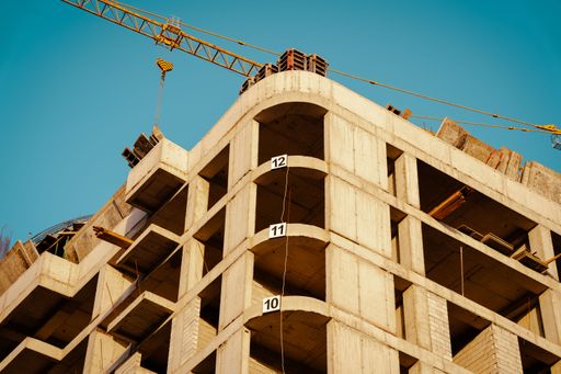 A construction site of a high-rise building under a clear blue sky with a crane in the background