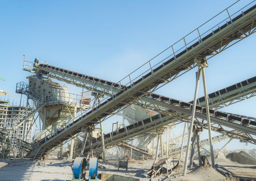 The Industrial conveyor belts in a gravel pit under a clear blue sky