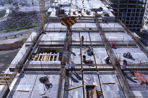 The Construction workers on a high-rise building site with cranes and rebar structures in the background