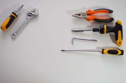 A set of hand tools including pliers, wrenches, and screwdrivers arranged on a white background