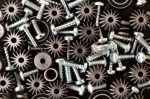 A close-up of various metal screws, washers, and springs in a pile