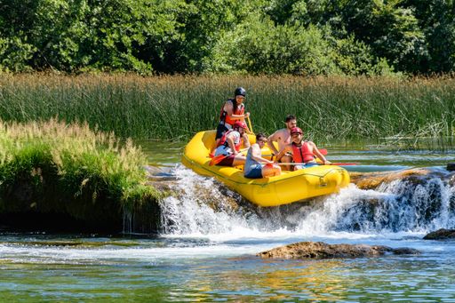 People in yellow whitewater raft having fun rafting on green river in summer. Mreznica river near Duga Resa in Croatia.