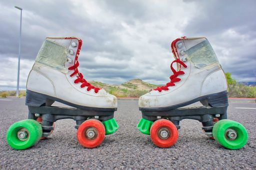 A shot of the roller skates with red and green wheels on the asphalt surface.
