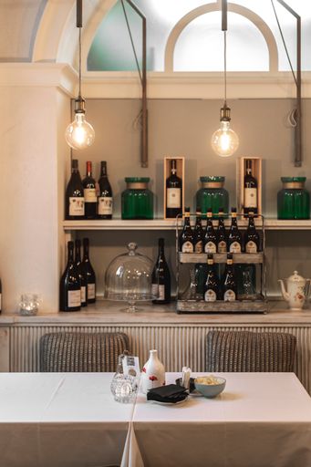 A vertical shot of an interior of a tea room with a small cozy table and bottles on a shelf