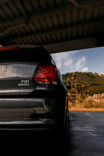 A vertical shot of a rear view of a gray car in the garage