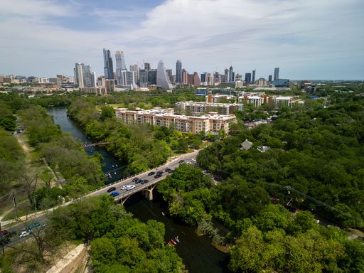 An aerial view of Austin cityscape with the downtown skyline and Lady Bird Lake surrounded by greenery on a sunny day in Texas, USA