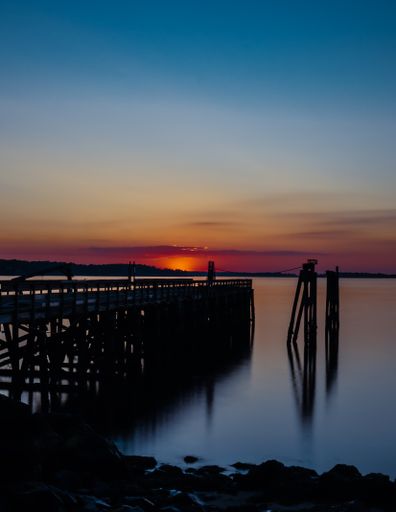 A stunning view of an empty wooden pier over the tranquil water during a peaceful beautiful sunset