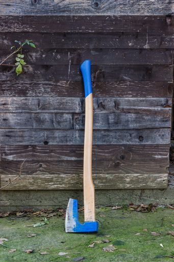 A vertical shot of an ax on wooden background