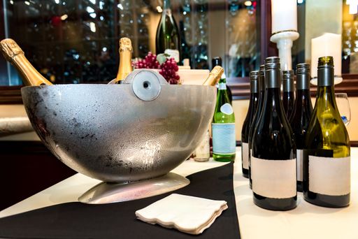 A close-up of a wine and champagne bottles setup at a party or event with a metal ice bucket.